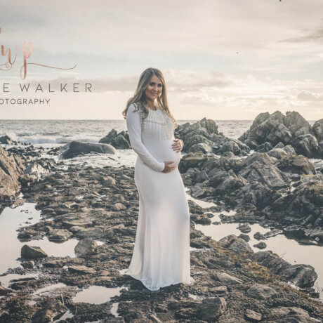 woman posing outdoors in off white maternity dress