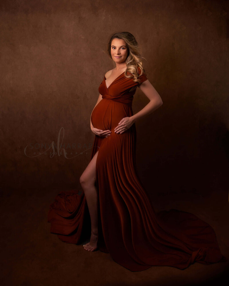 side pose of pregnant woman holding bump