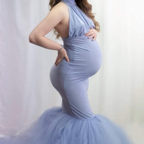 Pregnant woman wearing blue halter maternity dress by rosa amour