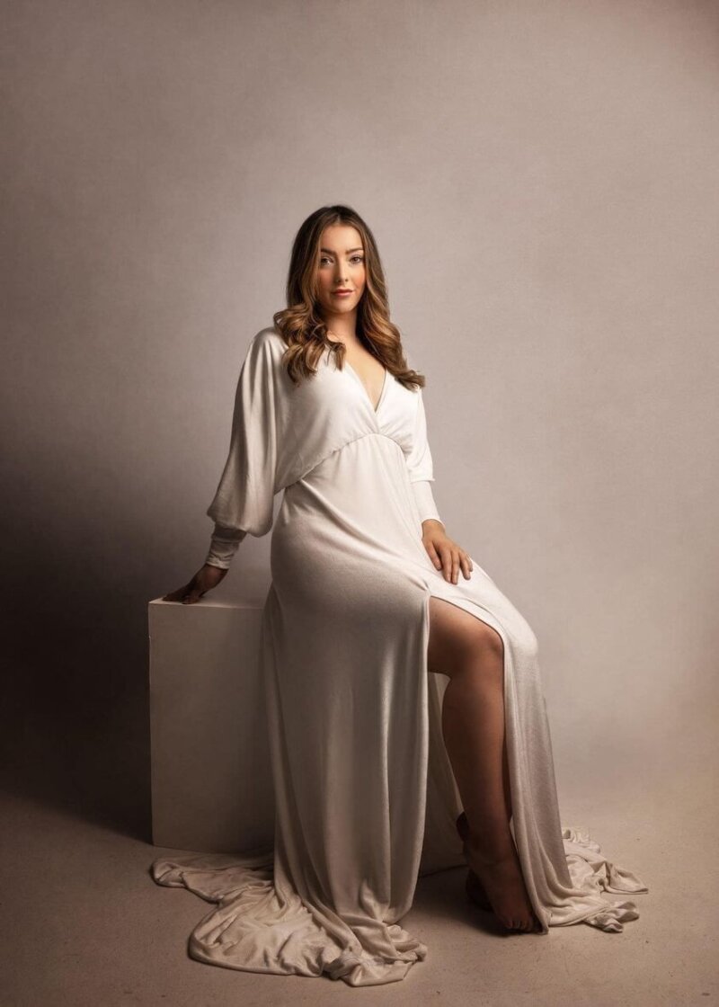 Women posed sitting on cube wearing off white rosa amour dress