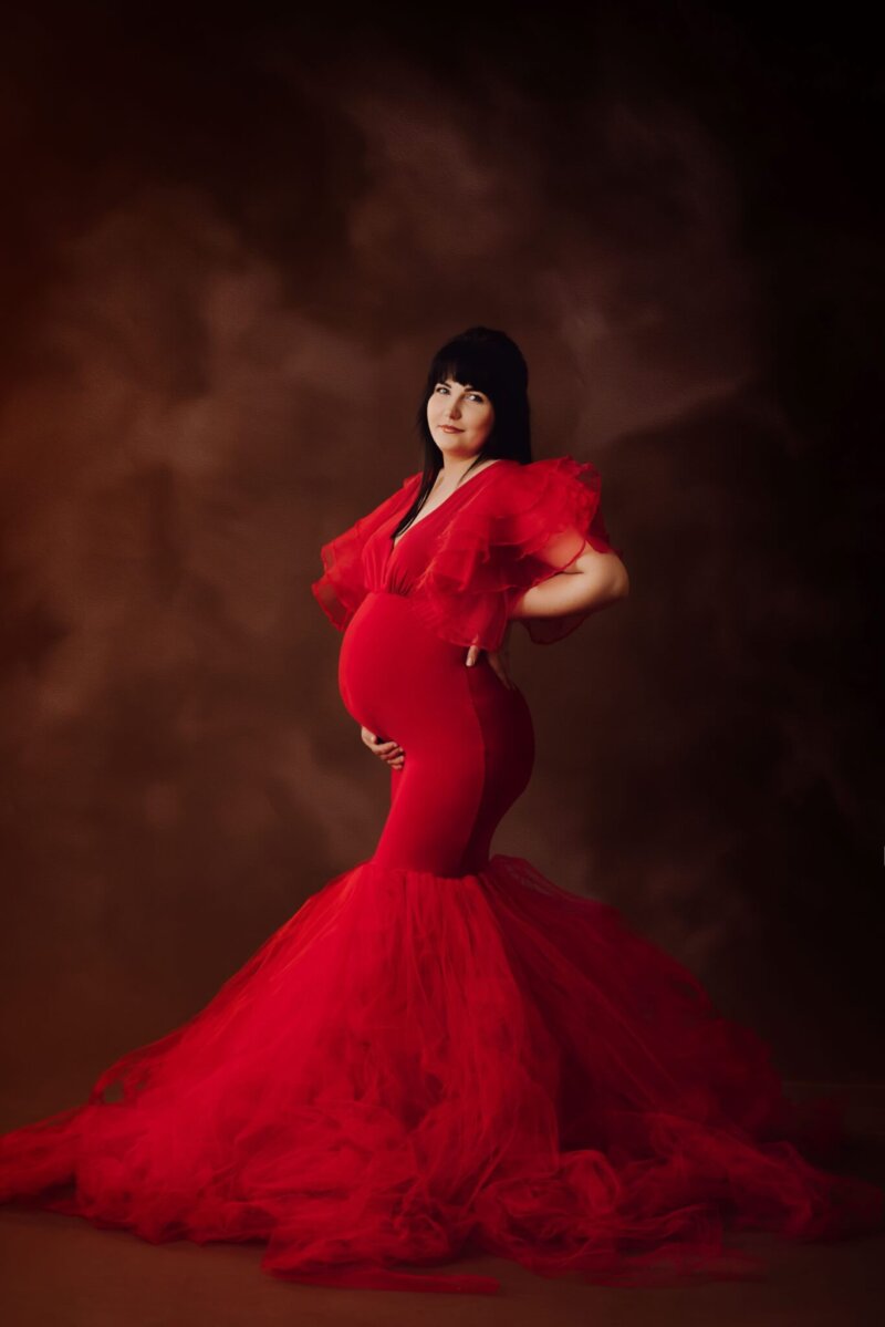 portrait of pregnant woman posing in red rosa amour gown