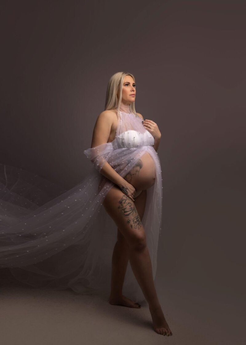 pregnant woman posed wearing a pearl tulle maternity dress