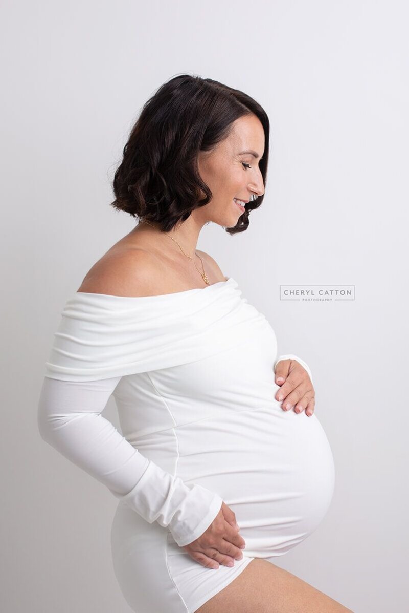 Side Posed pregnant woman wearing rosa amour white maternity bodysuit