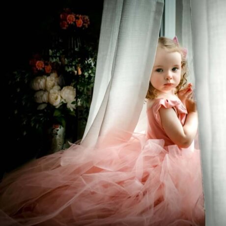 little girl posing in window under curtains wearing rosa amour children's gown