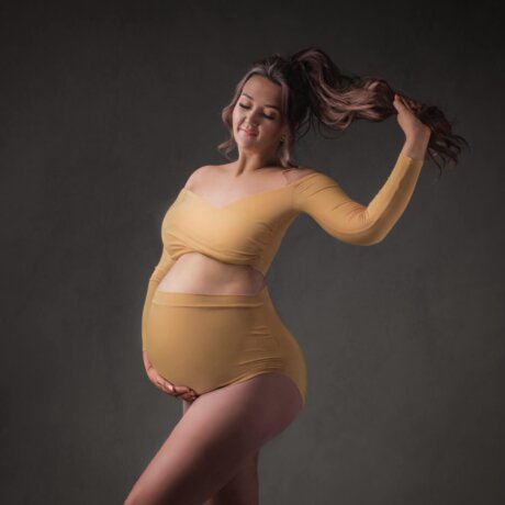 Pregnant woman posed wearing yellow 2 piece bodysuit by rosa amour