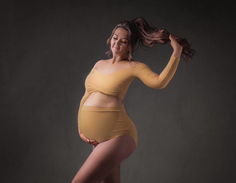 Pregnant woman posed wearing yellow 2 piece bodysuit by rosa amour