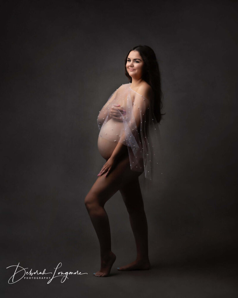 Pregnant women wearing sheer white cape/shawl with pearl details by Rosa Amour